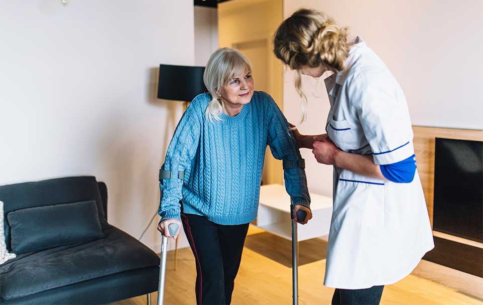 Live-in caregiver helping elderly woman to walk